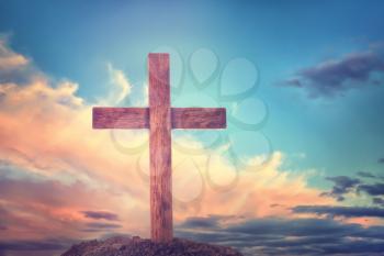 Grave with christian cross against blue cloudy sky�