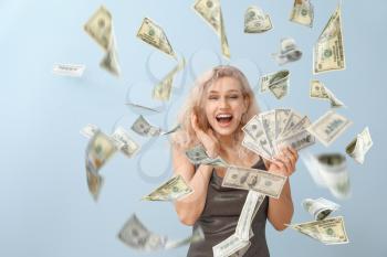 Beautiful young woman with flying money on grey background�