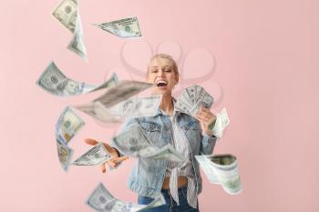 Beautiful young woman with flying money on color background�