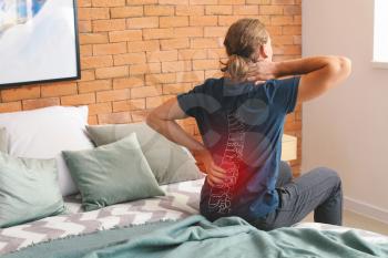 Young man suffering from back pain at home�