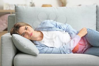 Young woman suffering from menstrual cramps at home�
