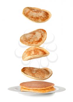 Tasty pancakes falling on plate against white background�