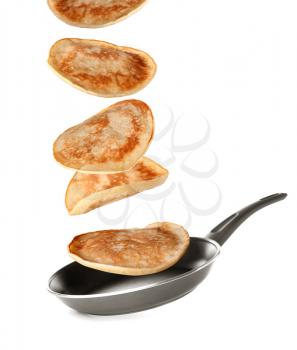 Tasty pancakes falling on frying pan against white background�