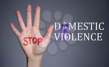 Female hand with text STOP DOMESTIC VIOLENCE on grey background�