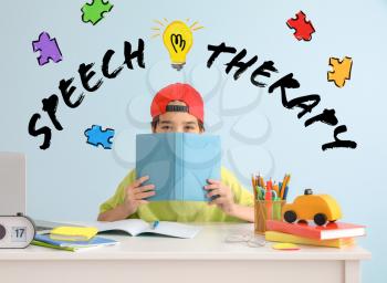 Little boy with book at table and text SPEECH THERAPY on color background�