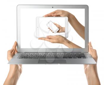 Hands holding laptop with gadgets on screen against white background�