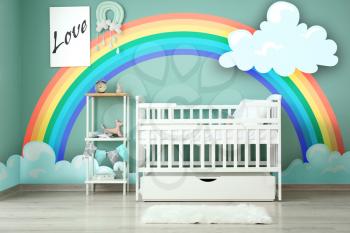 Interior of modern baby room with crib and painting of rainbow on wall�