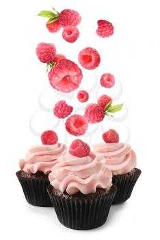Delicious cupcakes and falling raspberry on white background�