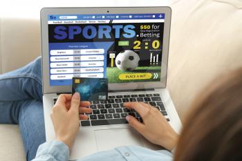 Young woman with credit card placing sports bet at home�