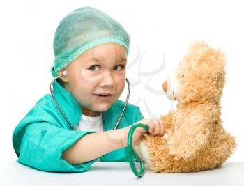 Royalty Free Photo of a Little Girl in Doctor's Scrubs Listening to Her Teddy Bear's Heart
