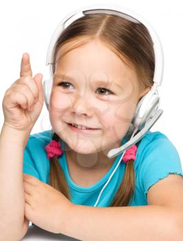 Cute young girl is working as an operator at helpline talking using headset, pointing with her finger up, isolated over white