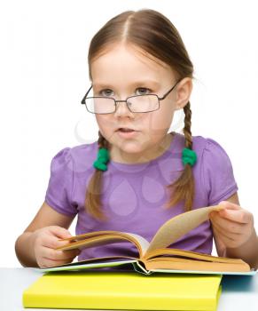 Cute little girl reading book wearing glasses, isolated over white