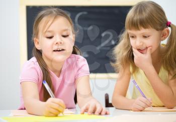 Cute little girls are writing using a pen in preschool