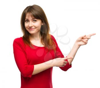 Portrait of a young woman pointing to the right using both hands, isolated over white