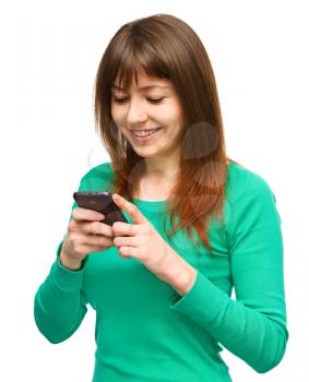 Young cheerful woman is typing sms message on her phone, isolated over white