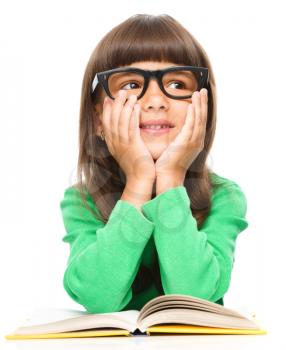 Young girl is daydreaming while reading book and wearing glasses, isolated over white