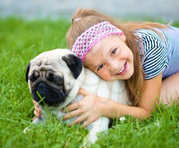 Little girl and her pug dog on green grass, outdoor shoot