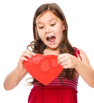 Portrait of a sad little girl tearing red heart apart, isolated over white