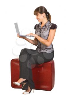 Royalty Free Photo of a Woman Sitting on Luggage Holding a Laptop