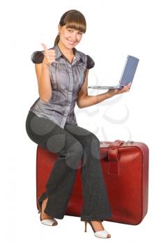Royalty Free Photo of a Woman on a Suitcase Giving Thumbs Up