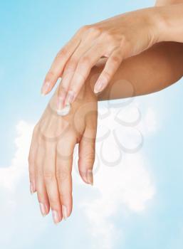 Two woman hands with moisturizer body cream against the sky