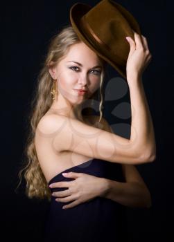Portrait of young pretty girl with a hat on dark background.