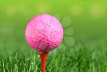 pink golf ball on a tee over green grass outdoors