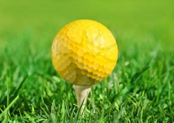 yellow golf ball on a tee over green grass outdoors