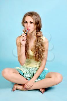 Portrait of young pretty woman with a multicolored lollipop