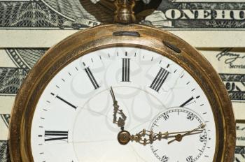 Time and Money concept image.
us currency and a pocket watch portray time and money