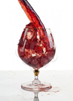 Red wine being poured into a wine glass.Isolated on white