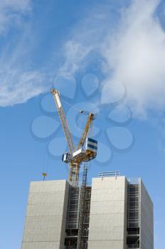 Construction crane and building under construction against blue sky