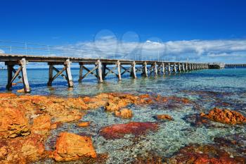 Sea landscape with wooden pier and orange stones
