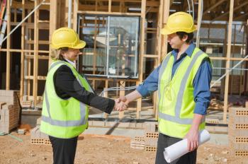 civil engineer and worker shaking hands at the construction site