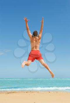 
muscular young man jumping on the beach 
