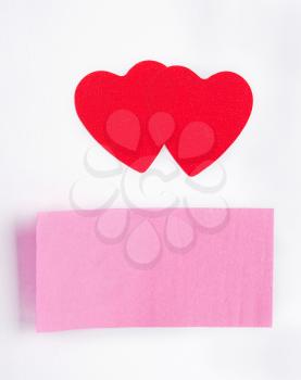Two red hearts and a sticky-note stuck on paper sheet