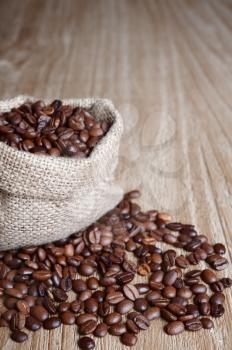 burlap sack of coffee beans on old wooden table.Shallow DOF