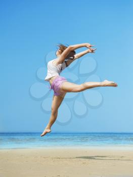 Beautiful energetic young woman jumping on the beach