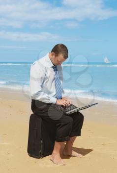 young businessman working with laptop on the beach 
