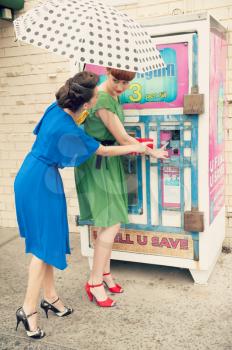 Two beautiful girls in retro style near a water machine