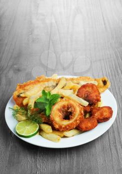 Seafood dish with crumbed fish,calamari,prawn and potato chips on vintage table 
