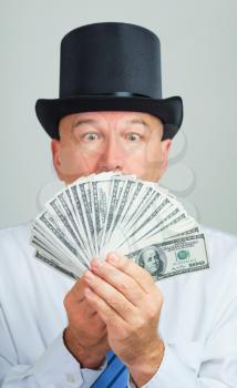 Surprised and amazed middle aged man in a retro top hat with money.Focus on the cash. 