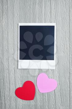 Valentines Day hearts and blank instant photo on vintage wooden background