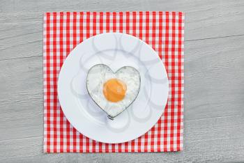 Fried egg  in heart shape on vintage table. Breakfast for a loved one