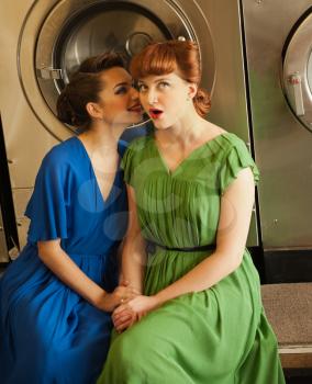 Two beautiful girls in retro style sitting together in laundry.Shallow DOF