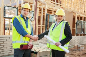 civil engineer and worker shaking hands at the construction site