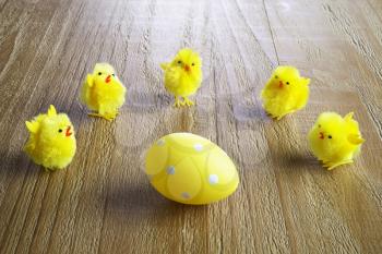 Yellow easter egg and chickens on wooden background