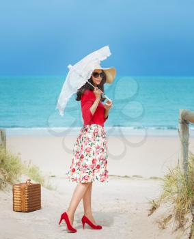 beautiful lady in red traveler in retro style dress  on the beach