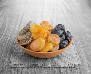 Dried pitted fruits on a wooden background 