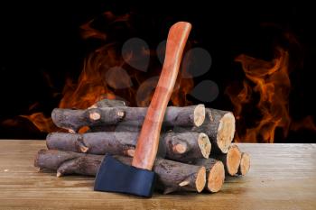 stack of firewood logs and axe on a wooden surface
